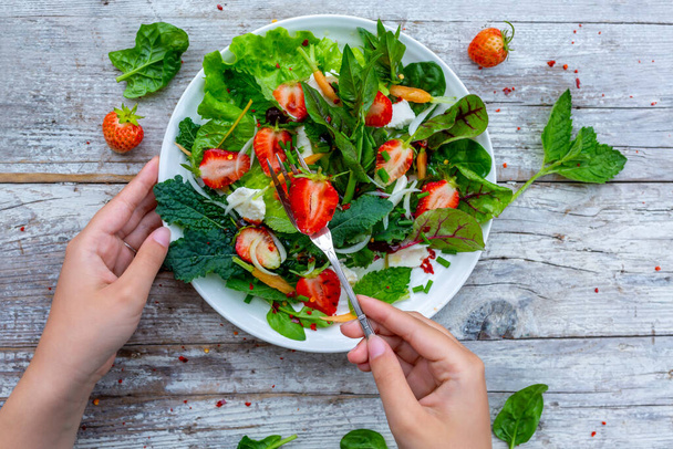 Μια υγιεινή και νόστιμη σαλάτα φτιαγμένη από φρέσκες φράουλες και φύλλα λαχανικών. Χορτοφαγικά τρόφιμα. - Φωτογραφία, εικόνα