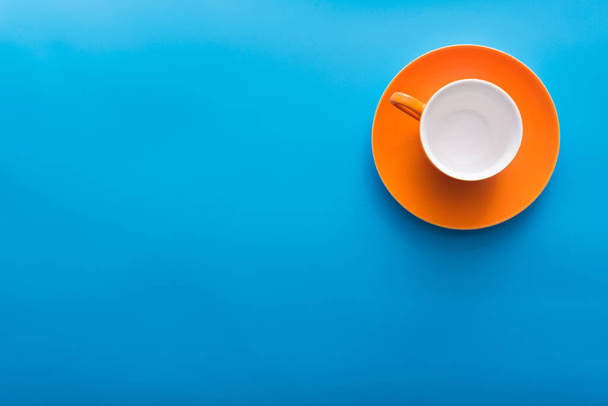 青い背景に空のオレンジコーヒーカップトップビュー - 写真・画像