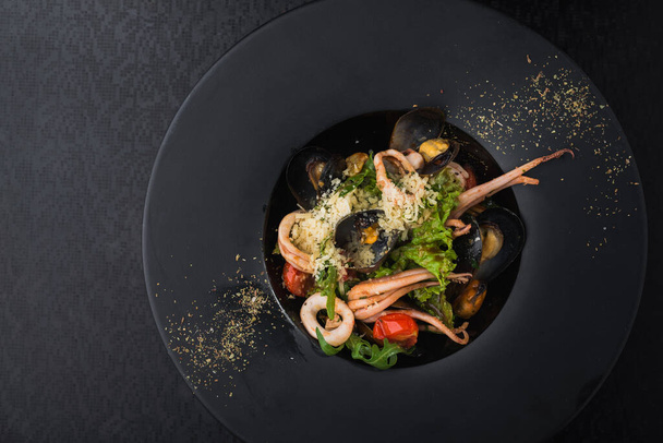 frutti di mare, calamari e cozze in un piatto nero. piatto al ristorante - Foto, immagini