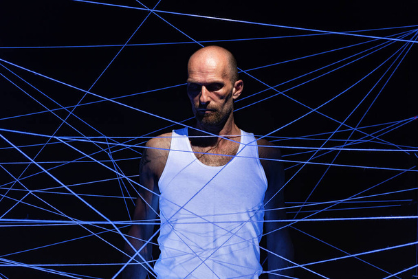 Photo of adult man tangled in white threads in neon light - Photo, Image