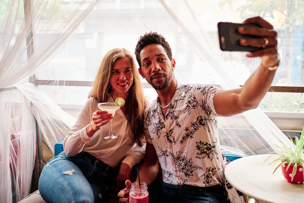 joven interracial pareja en amor tomando selfie en el bar
 - Foto, Imagen