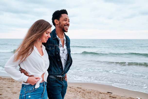 jovem casal interracial na praia dando um passeio
 - Foto, Imagem