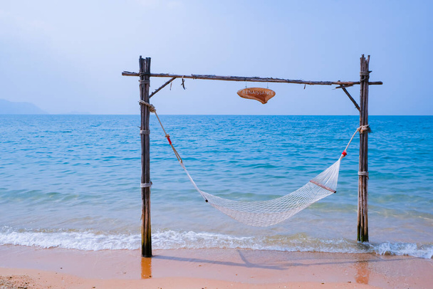 Romantic cozy hammock on the tropical beach by the sea. Peaceful seascape. Beautiful blue sky over calm sea with sunlight reflection. Relax, travel concept, travelling. Copy space banner. - Zdjęcie, obraz