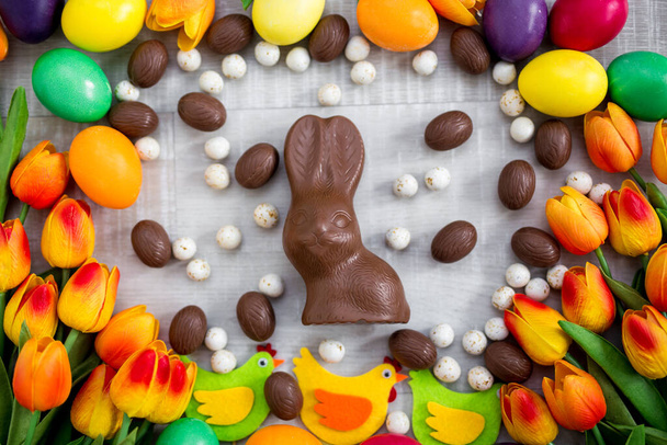 Fondo de Pascua - primer plano de huevos de colores, decoraciones, tulipanes, conejito de chocolate y dulces
 - Foto, Imagen