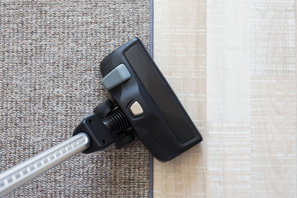 Koncepcja sprzątania - nowoczesny odkurzacz na dywanie i drewniane tło parkietu - Zdjęcie, obraz