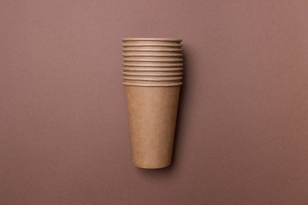 Eco-friendly cardboard cups lie on a brown color paper background. Mock-up. Close-up. The concept of ecology. - Photo, Image
