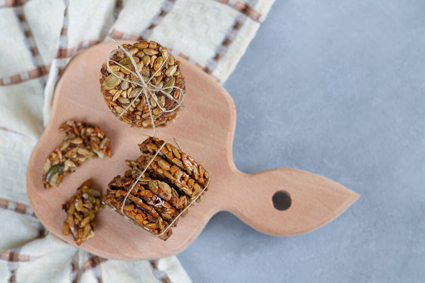 Питательный здоровый десерт с семечками подсолнуха, семян тыквы и органического меда на деревянной доске с копировальным пространством сверху
 - Фото, изображение