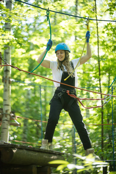 Blonde woman standing on the rope bridge entertainment in full insurance - Photo, Image