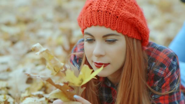 Портрет красивої жінки з червоним капелюхом лежить в жовтому осінньому листі. Жіноча модель насолоджується життям на відкритому повітрі природа фон 4k повільний рух
 - Кадри, відео