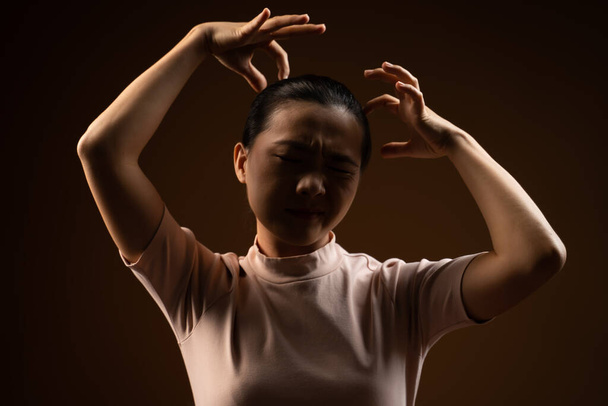 Aziatische vrouw verveeld en geïrriteerd, krassen op haar hoofd, geïsoleerd staan op beige achtergrond. Slechte sleutel. - Foto, afbeelding