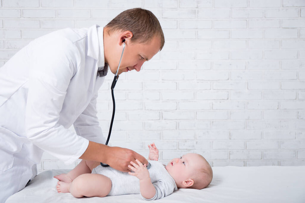 side view of doctor pediatrician examining little baby patient in hospital - Photo, Image