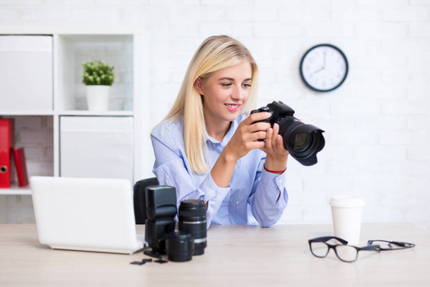 giovane fotografa seduta con computer e attrezzature fotografiche e scegliendo le migliori foto in ufficio moderno - Foto, immagini