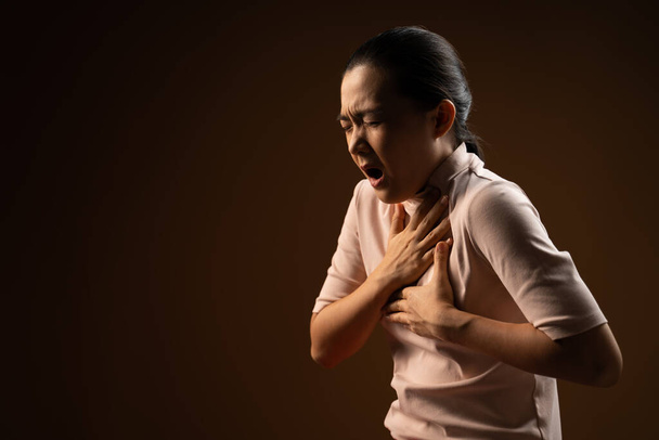Aasialainen nainen oli sairas rintakipu seisoo eristetty beige tausta. Matala avain - Valokuva, kuva