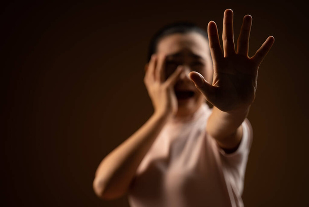Asian woman scared screaming covering face by her hands standing isolated on beige background. Low key. - Photo, Image