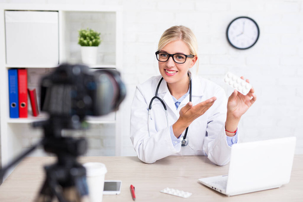 ヘルスケアとブログのコンセプト-若い陽気な美しい女性医師の記録vlogビデオ医学について - 写真・画像