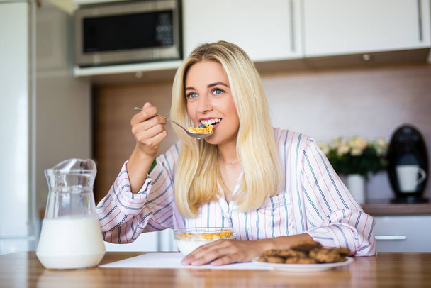 petit déjeuner sain - jeune belle femme gaie manger des flocons de maïs avec du lait à la maison - Photo, image
