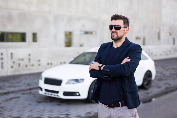 Όμορφος επιχειρηματίας ποζάρει με το λευκό του αυτοκίνητο - Φωτογραφία, εικόνα