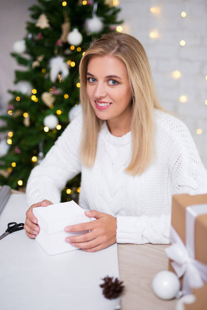 hermosa mujer rubia embalaje regalos de Navidad en sala de estar decorada
 - Foto, Imagen