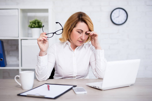 ストレスと仕事の概念-ストレスや疲れ成熟した女性医師が現代のオフィスに座って - 写真・画像
