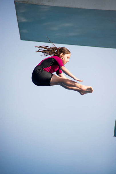 Pike dalışı. Kafkas kadın 8 yaşında, neopren kısa sörf kıyafeti giymiş 5 mether dalış platformundan dalış yapıyor. Yaz, spor ve eğlence konsepti. - Fotoğraf, Görsel