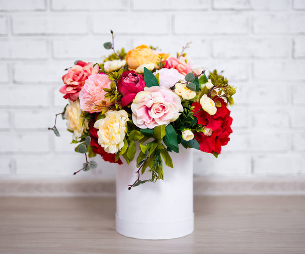 beau bouquet de fleurs d'été en boîte ronde sur fond de mur de briques blanches - Photo, image