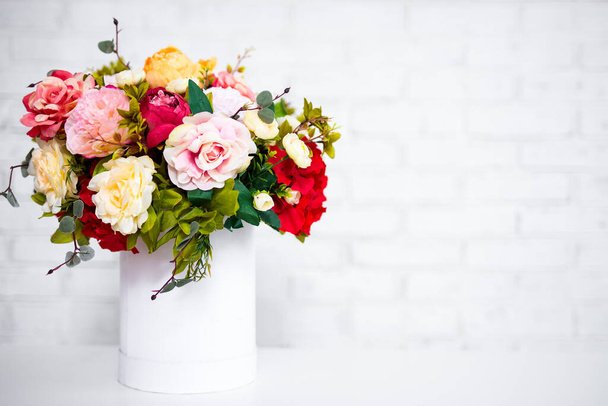 όμορφο μπουκέτο από λουλούδια του καλοκαιριού σε στρογγυλό κουτί πάνω από λευκό φόντο τούβλο τοίχο με αντίγραφο χώρο - Φωτογραφία, εικόνα