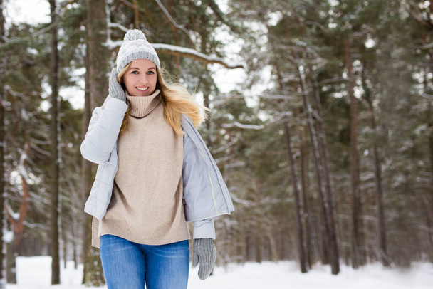 portrait of young beautiful blond woman walking in winter forest - Photo, Image