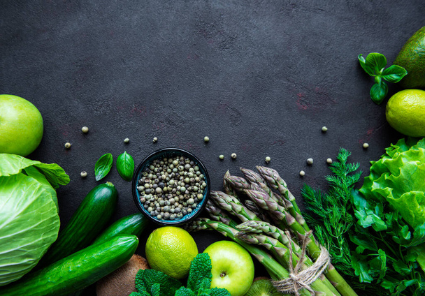 Sağlıklı vejetaryen gıda konsepti, detoks diyeti için taze yeşil gıda seçimi, elma, salatalık, kuşkonmaz, avokado, limon, siyah beton arka planda salata üstü görünümü. - Fotoğraf, Görsel