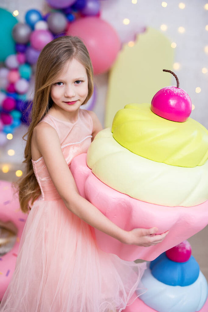 concepto de comida poco saludable - retrato de niña linda sosteniendo magdalena enorme
 - Foto, imagen