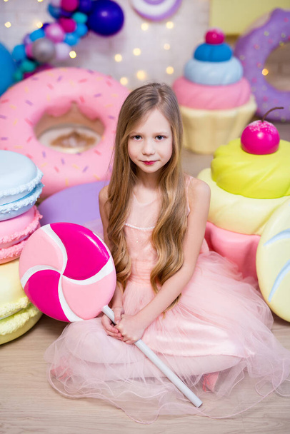 Süßwarenkonzept - süßes kleines Mädchen mit riesigen Süßigkeiten und Gebäckdekorationen - Foto, Bild