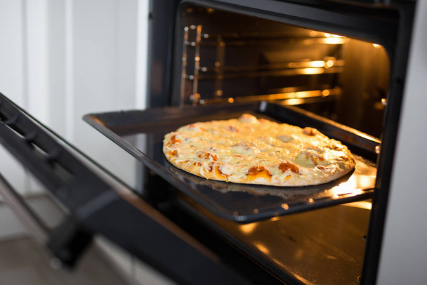 close up of tasty homemade cheese pizza in hot oven - Fotó, kép