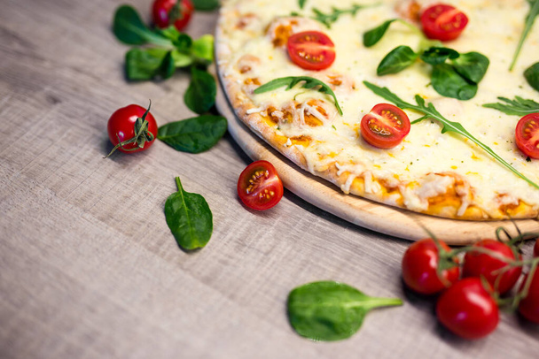 Закрыть пиццу с помидорами и травами и скопировать место на фоне деревянного стола
 - Фото, изображение