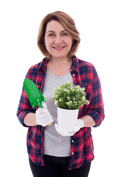 portrait of mature woman gardener with potted plant and shovel isolated on white background - Photo, image