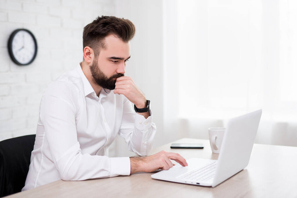 portré jóképű szakállas férfi használ laptop az irodában - Fotó, kép