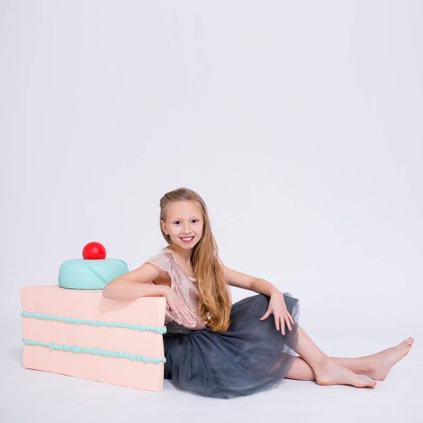 χαριτωμένο κοριτσάκι με μεγάλο κομμάτι κέικ και αντίγραφο χώρο πάνω από λευκό φόντο - Φωτογραφία, εικόνα