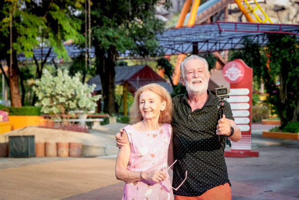 Ältere Paare verbringen am Sommerwochenende Zeit miteinander im Freizeitpark, Senioren hängen herum und amüsieren sich im Freizeitpark. Opa und Oma fotografieren ihre Zeit auf Jahrmarkt  - Foto, Bild