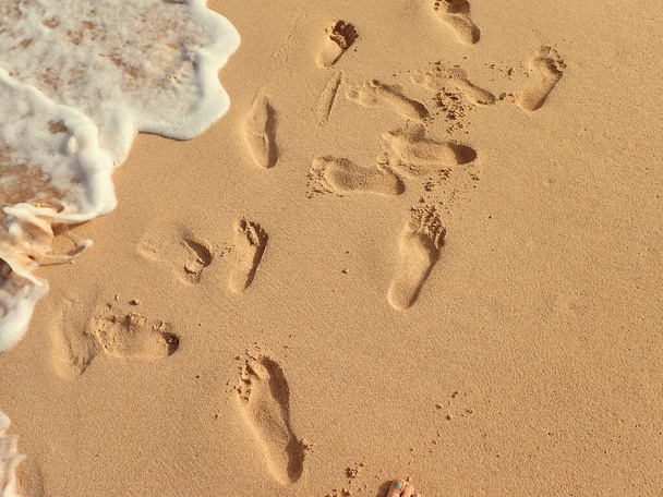 kauniit jalanjäljet hiekassa meren rannalla lämpimänä kesäpäivänä, - Valokuva, kuva