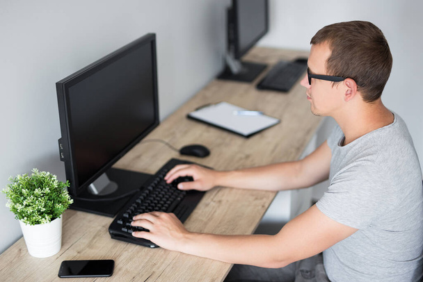vista lateral del joven utilizando el ordenador en casa o en el trabajo - pantalla en blanco con espacio para copiar
 - Foto, imagen
