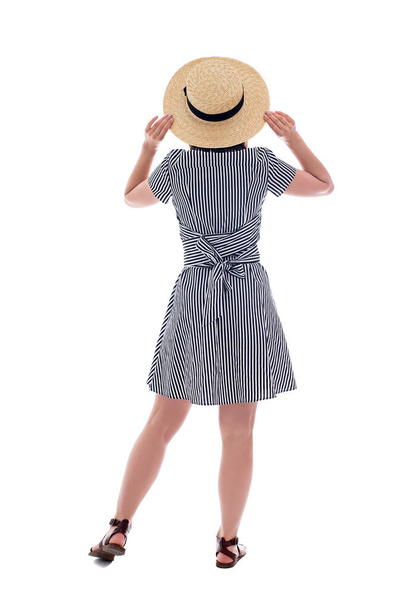 白い背景に隔離された縞模様のドレスと麦藁帽子の若い女性のバックビュー - 写真・画像