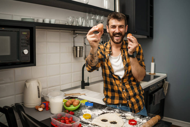 Молодий чоловік розважається, роблячи печиво на своїй кухні
. - Фото, зображення