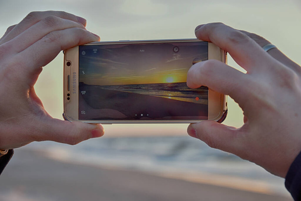 mooie zonsondergang aan zee fotograferen van een moderne mobiele telefoon - Foto, afbeelding
