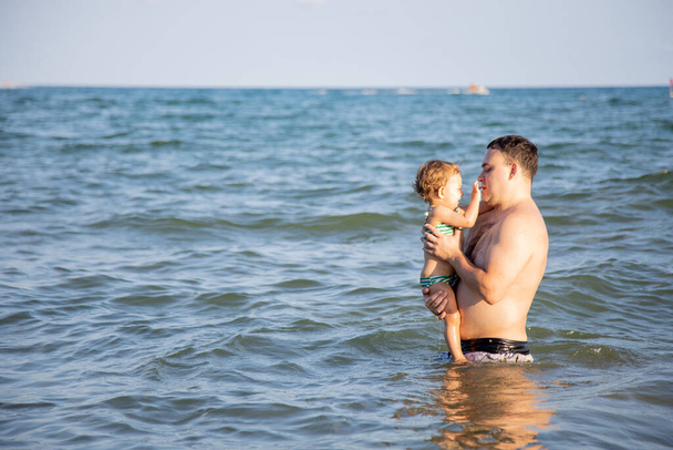 conceito de felicidade familiar. O melhor pai. pai abraços um pouco bonito criança filha na água de um mar quente confortável
. - Foto, Imagem