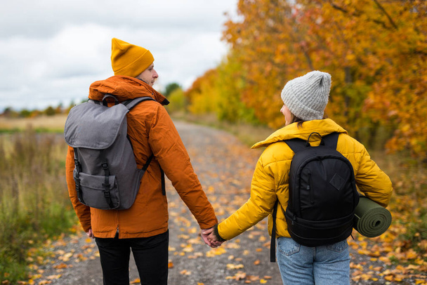 Sonbahar ormanlarında gezen sırt çantalı çiftlerin arka görüntüsü. - Fotoğraf, Görsel
