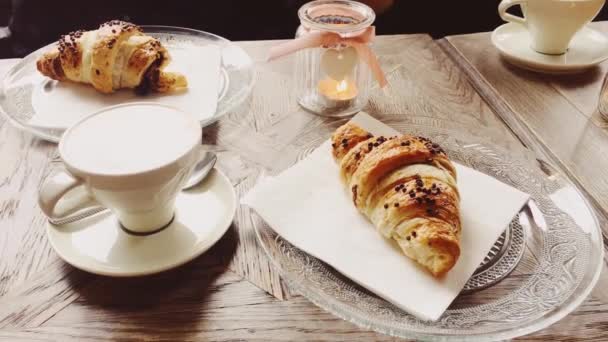 Cappuccino και κρουασάν σοκολάτας σε cafe, φλιτζάνι καφέ και γλυκό για πρωινό, φαγητό και είδη ψησίματος - Πλάνα, βίντεο