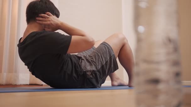 Asiatischer Mann bei Sitzgymnastik im Liegen auf dem Boden zu Hause, Heimfitnesstraining, während der Hausquarantäne fit bleiben, in Form bleiben - Filmmaterial, Video