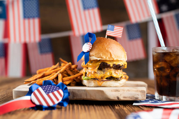 Fourth of July celebration. American flag and decorations. Burgers on rustic wooden table. - Foto, Bild