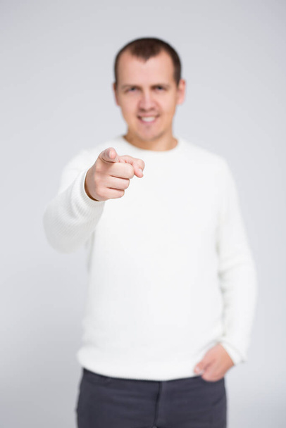 portrait of young cheerful man pointing his finger at you over gray background - Photo, Image
