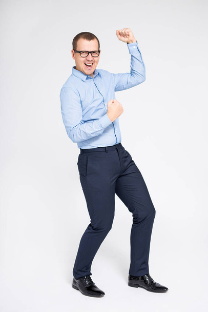 retrato de joven empresario alegre celebrando algo y bailando sobre fondo gris
 - Foto, Imagen