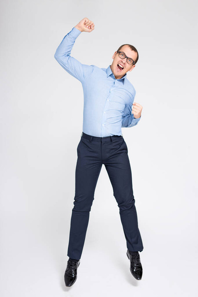 success concept - cheerful young handsome businessman celebrating something and jumping over gray background - Foto, Imagen
