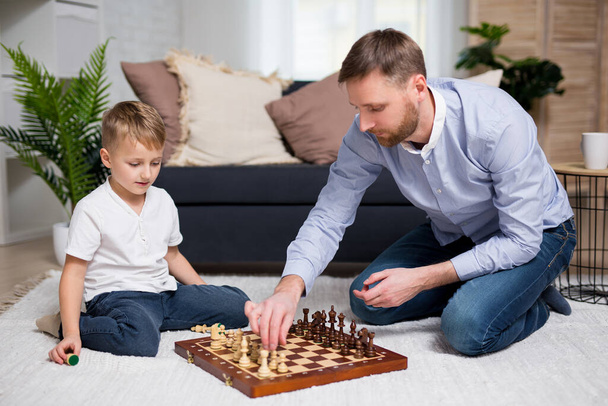 fiatal apa sakkozik az ő kis aranyos fia otthon - Fotó, kép